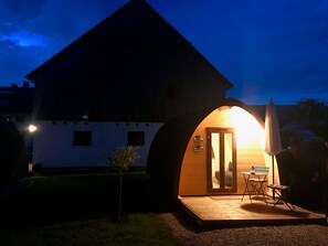 Een gezellig, halfopen constructie met een houten terras, een kleine tafel en stoelen, en een deur die naar binnen leidt.