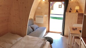 Ein gemütliches Holzhaus-Zimmer mit einem Bett, einem kleinen Schreibtisch und einem Fenster.