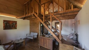 A rustic wooden interior with a loft bedroom, a dining area, and a seating area. - Quinta do Ragal - Glamping (Fundao)
