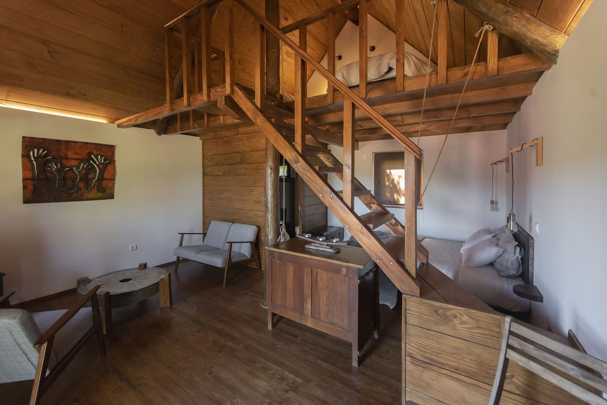 Un intérieur rustique en bois, avec une chambre à coucher située en mezzanine, un coin repas et un espace salon.