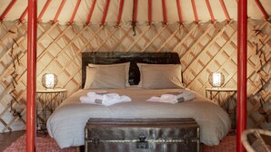A traditional yurt with a four-poster bed, wooden floor, and a central fire pit. - Quinta do Ragal - Glamping (Fundao)