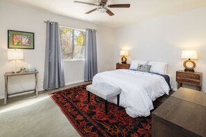 A bedroom with a bed, bedside tables, a desk, a chair, a ceiling fan, and a window with curtains. - The Joshua Tree Duo - A & B (Joshua Tree)