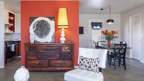 Un salon avec un meuble en bois, un canapé blanc et un coin repas comprenant une table et des chaises.