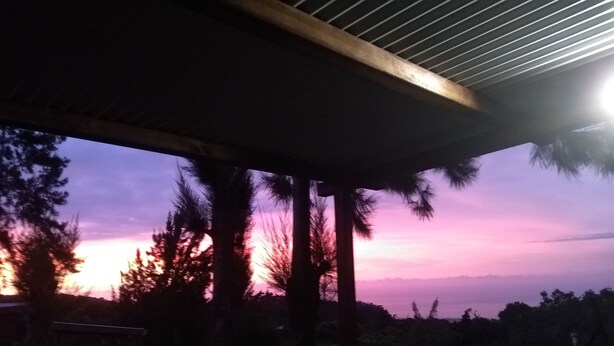 A wooden balcony with a view of a sunset. - DOMAINE DECOTTE BUNGALOW in the heart of nature (Sainte-Suzanne)