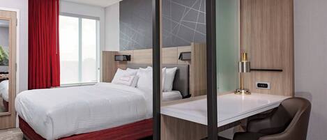 Una habitación de hotel moderna con una cama grande, un escritorio y una silla.