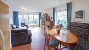 Un vaste espace de vie comprenant un canapé, une table à manger, des chaises et une grande fenêtre.