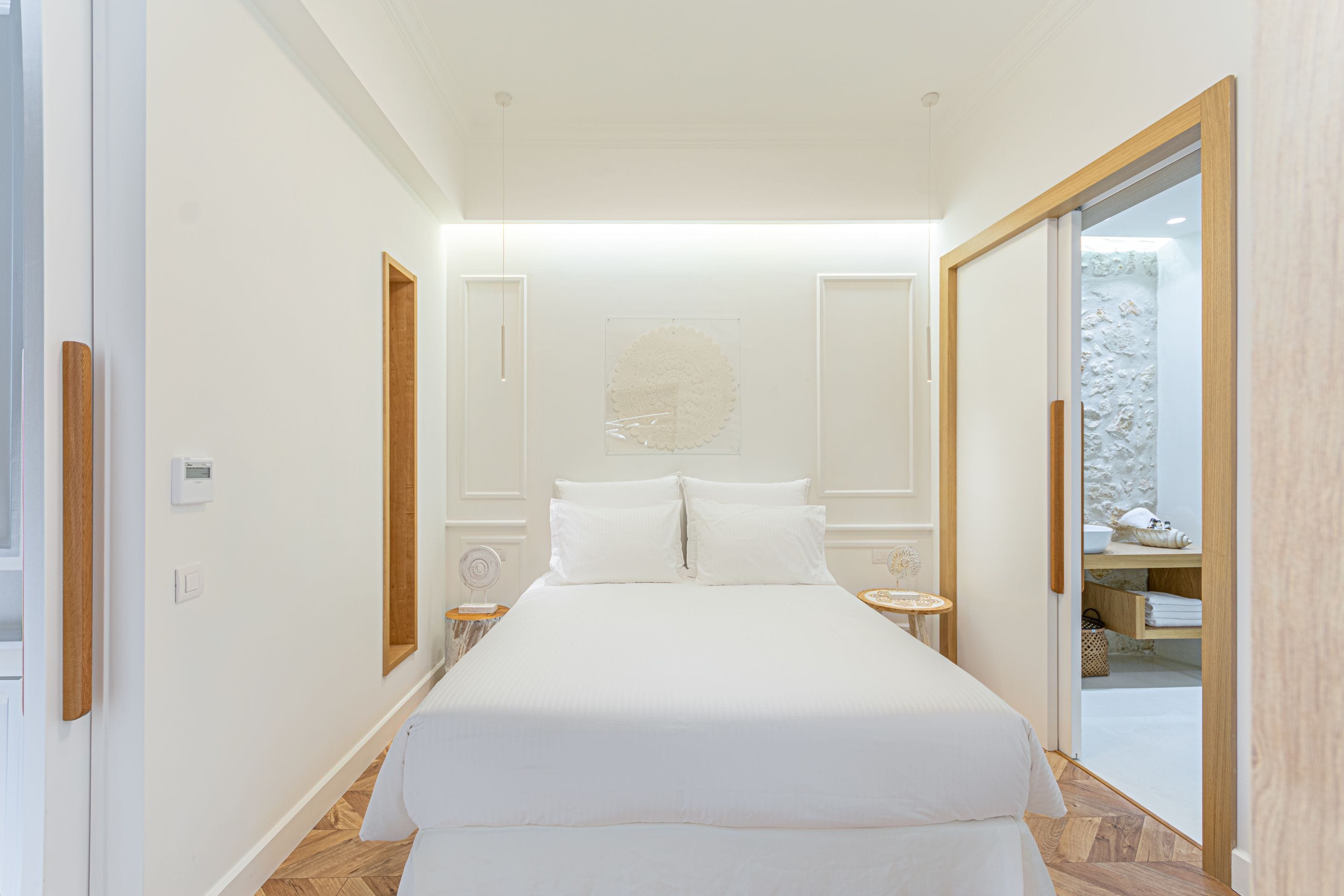 A modern bedroom with a large bed, a bedside table, and a small table with a lamp.