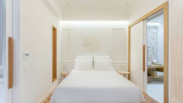 A modern bedroom with a large bed, a bedside table, and a small table with a lamp.