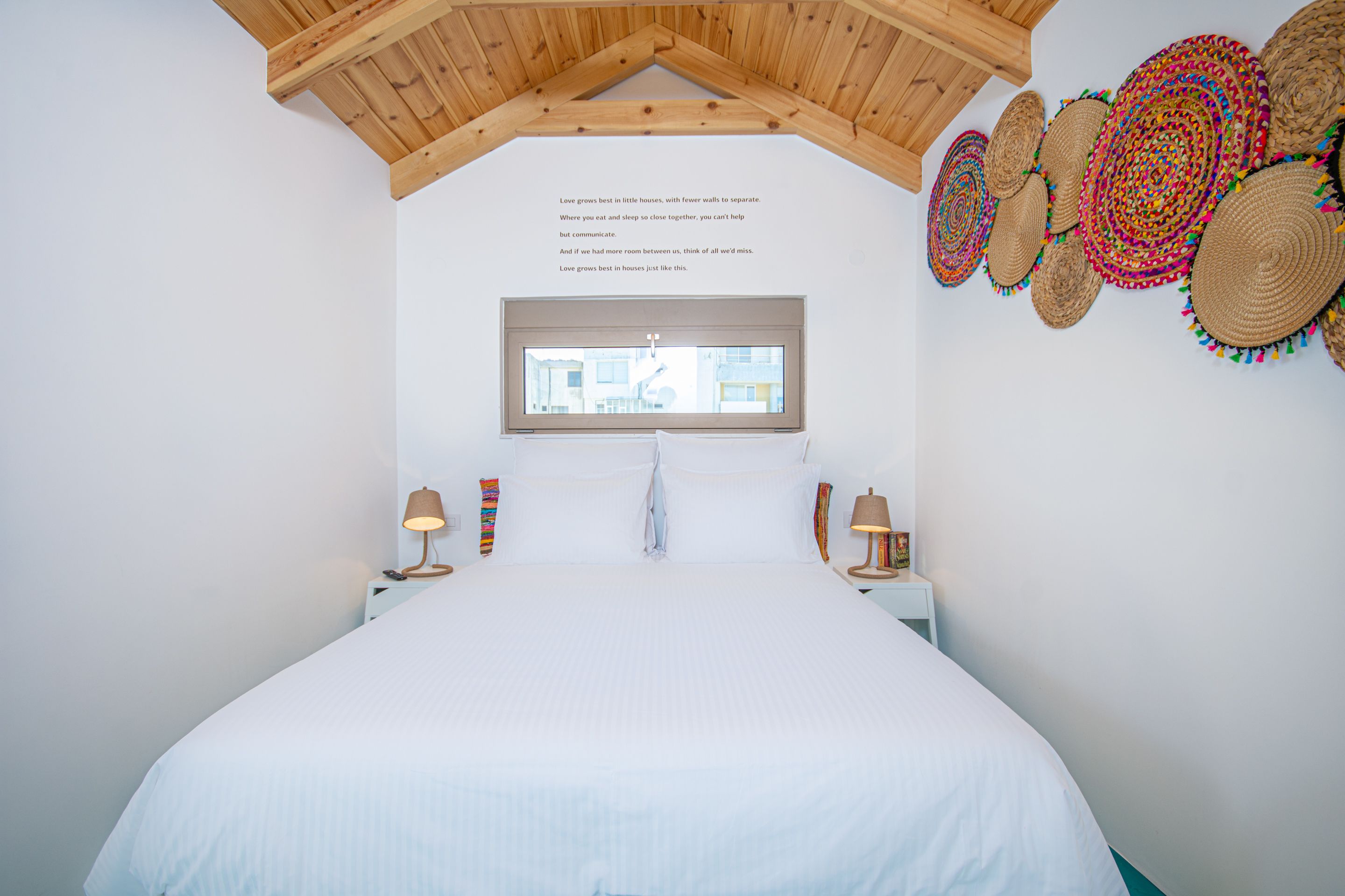 Ein Schlafzimmer mit einem großen Bett, einem Fenster und einer Decke mit Holzbalken.