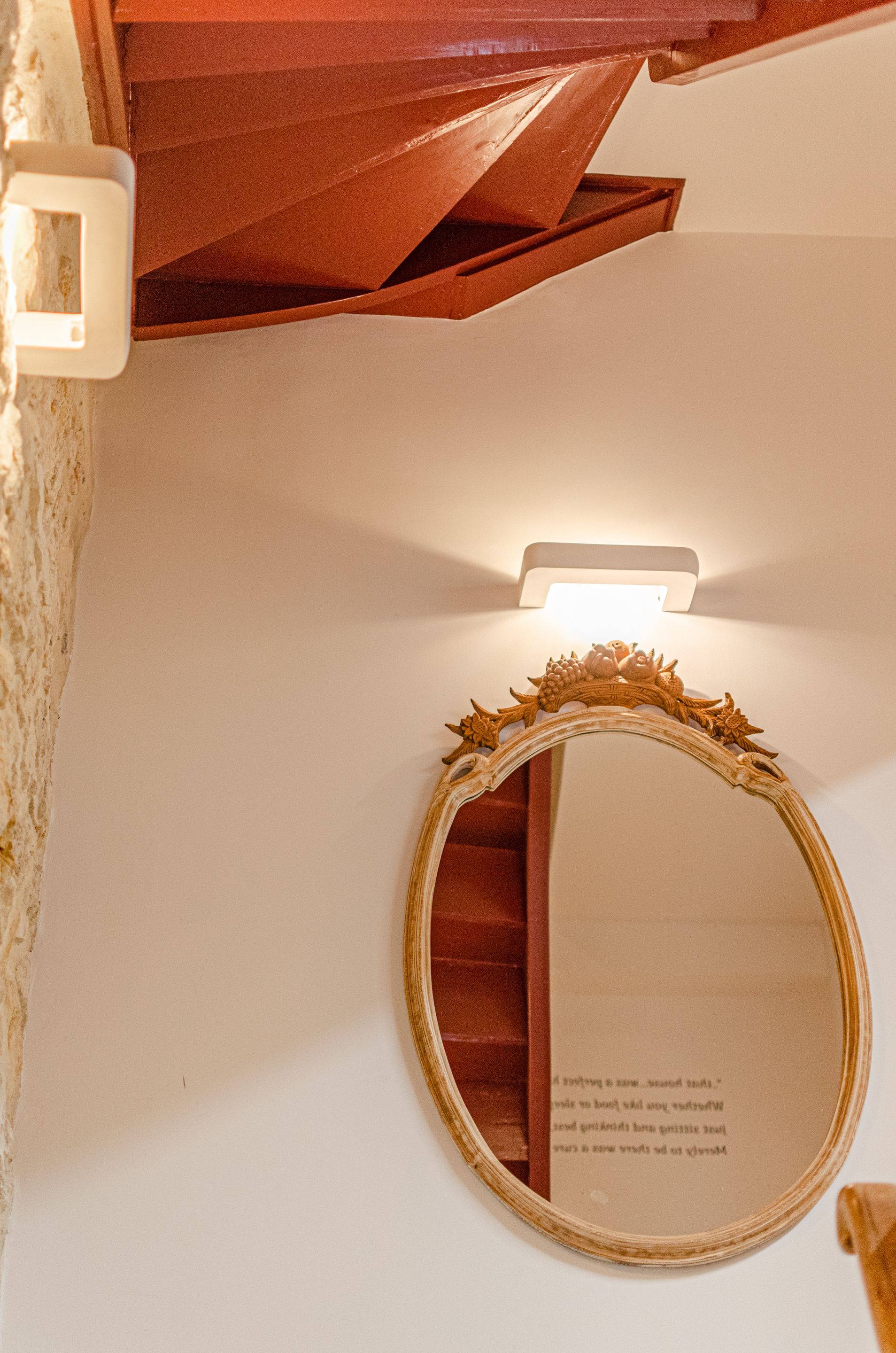 A mirror with an ornate frame, a light fixture above it, and a partially visible door.