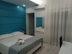 A modern hotel room with a large bed, a bedside table with a plant, and a mirror on the wall. - Dreams Tropea Mare (Tropea)
