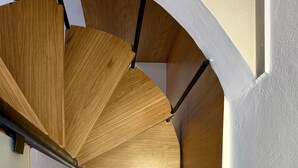 A spiral staircase with wooden steps and black handrails. - Sotoportego (Χανιά)