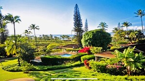 Un exuberante jardín con piscina, palmeras y un gran árbol en el centro.