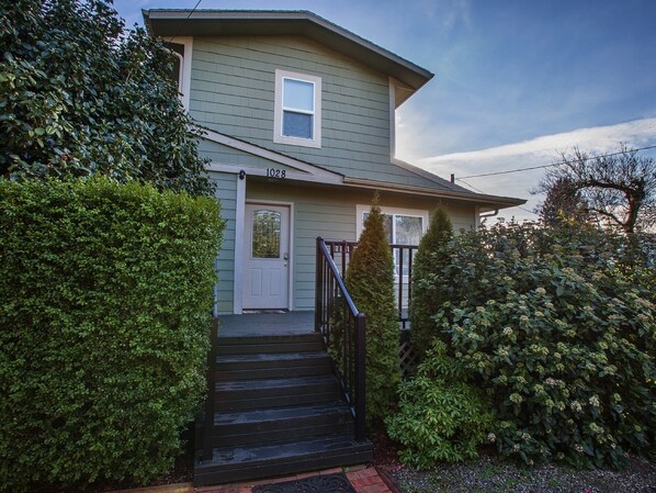 A two-story house with a front porch, a door with a glass panel, and a mailbox.