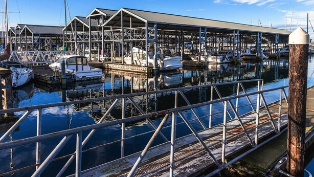 Een jachthaven met verschillende boten afgemeerd, houten looppaden en een helderblauwe lucht.