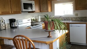 A kitchen with wooden cabinets, a microwave, a stove, a sink, and a dishwasher. - Clean and cute,1 bed, 1 bath, small town setting across from city park. (Plains)