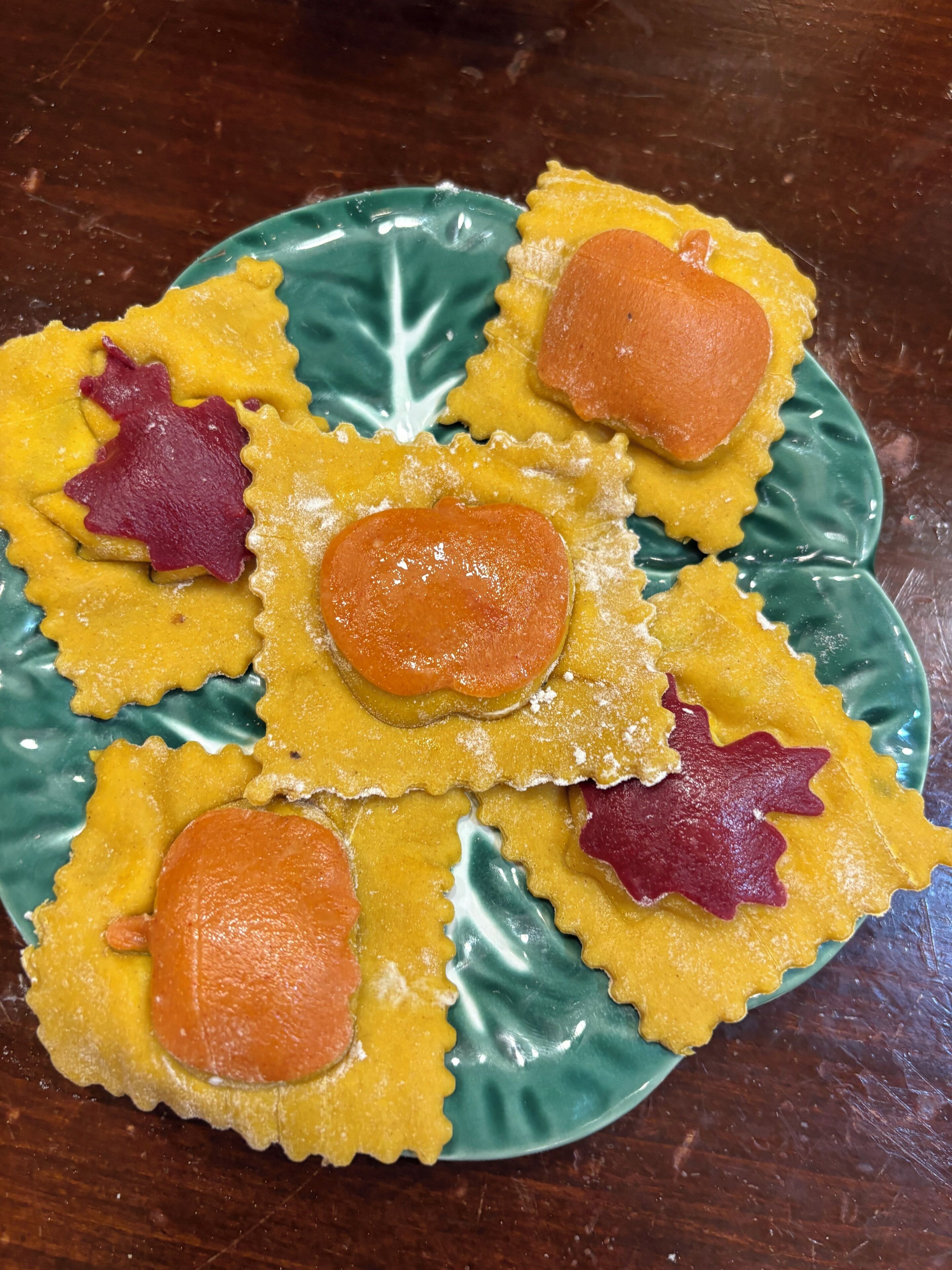 A plate of ravioli with a decorative leaf pattern on the rim.