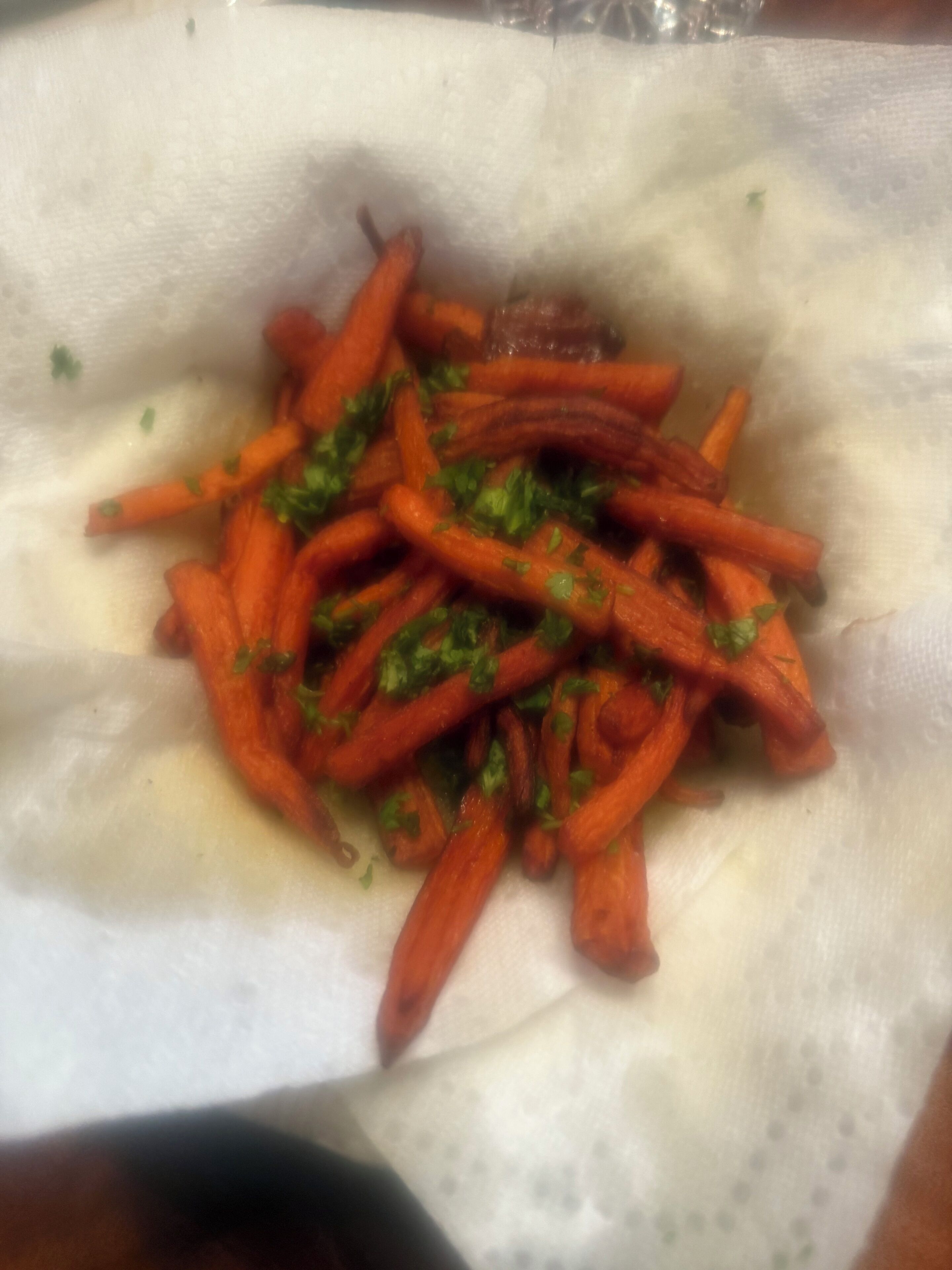 A close-up of a dish with julienned carrots and chopped herbs.