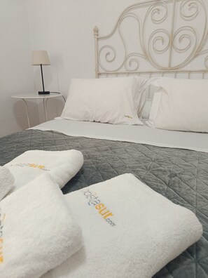 A neatly made bed with a grey quilt, white pillows, and a white headboard with decorative scrollwork. - Chalet La Costa, close to the beach and with Wifi (Chiclana de la Frontera)