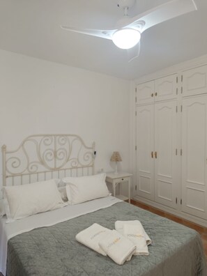 Un dormitorio con cama, mesita de noche, lámpara y armario.