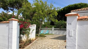 A stone-paved courtyard with white walls and a gate, surrounded by greenery and a blue chair. - Chalet La Costa, close to the beach and with Wifi (Chiclana de la Frontera)