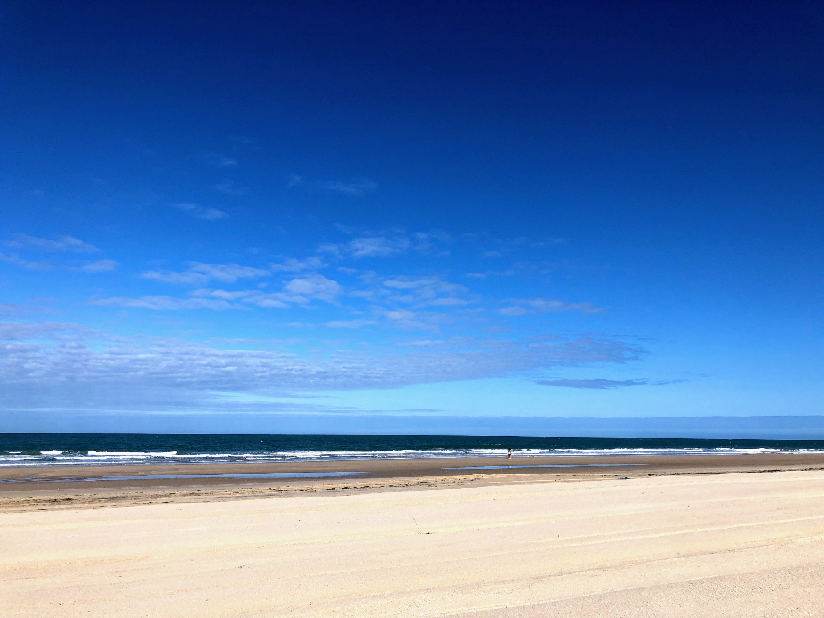 Ein Strand mit blauem Himmel und dem Meer.