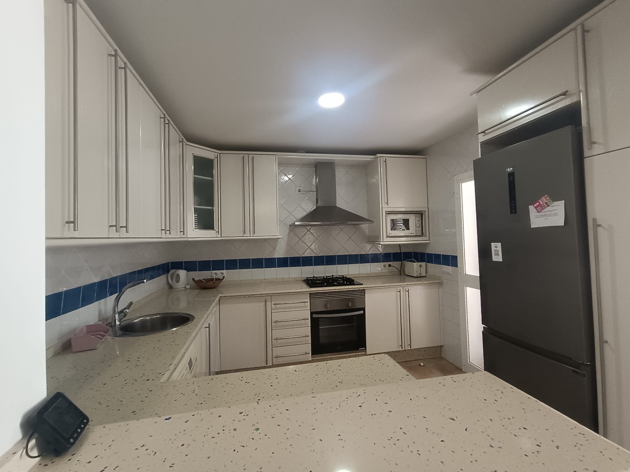 A compact kitchen with white cabinets, a microwave, a stove, and a refrigerator.