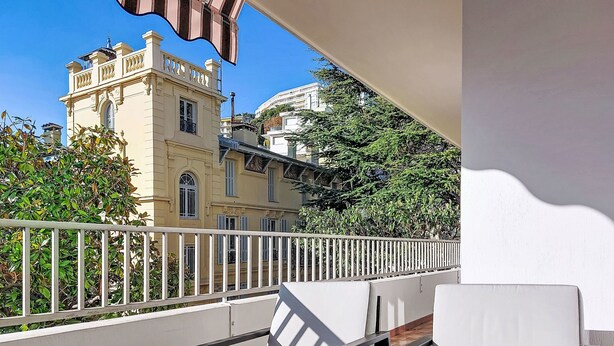 A balcony with white chairs and a view of a historic building with ornate architecture. - Le Clos tranquille by Interhome (Nice)