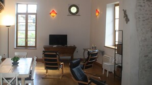 Ein geräumiges Wohnzimmer mit einem Holzespeisetisch, mehreren Stühlen, einem Fernseher und einem Kamin.