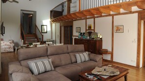 Ein geräumiges Wohnzimmer mit einem großen braunen Sofa, einem Holztisch und einer Treppe, die in einen oberen Bereich führt.