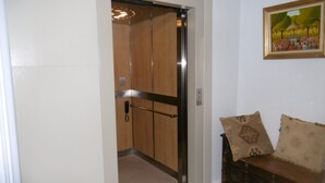 Een lift met een houten interieur en een telefoon aan de muur.