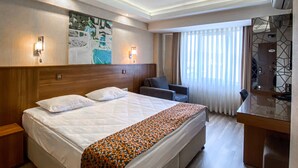Habitación de hotel con una cama grande, un escritorio, una silla y un aire acondicionado de pared.