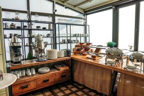 Una cocina con armarios de madera, una cafetera y repisas con cristalería y vajilla.