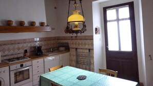 Una cocina con techo de madera, una lámpara colgante, salpicadero de azulejos y una mesa de comedor con sillas.