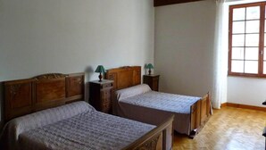Una habitación con dos camas de madera, techo de madera y una ventana con cortinas.