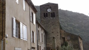 Un edificio histórico con una torre de reloj, que presenta una fachada de piedra tradicional y múltiples ventanas.