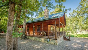 Eine rustikale Holzhütte mit Steinunterbau und einer Veranda mit Geländer.