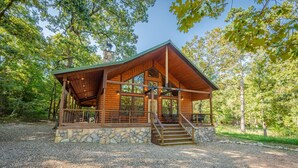 Eine Blockhütte mit Steinuntergrund, einer Veranda mit Sitzgelegenheiten und einer Treppe zum Eingang.