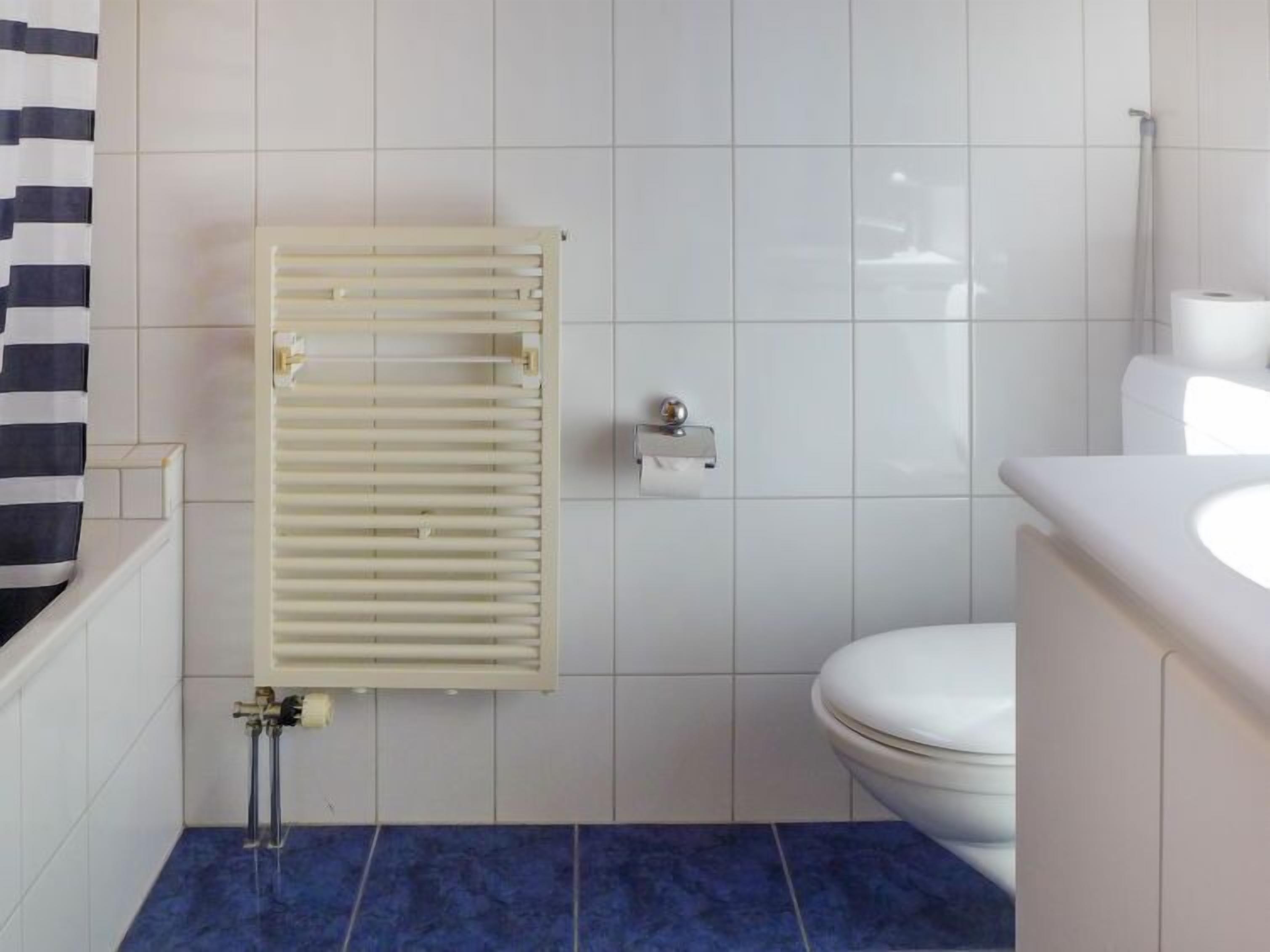 A bathroom with a white toilet, a towel rack, and a shower.