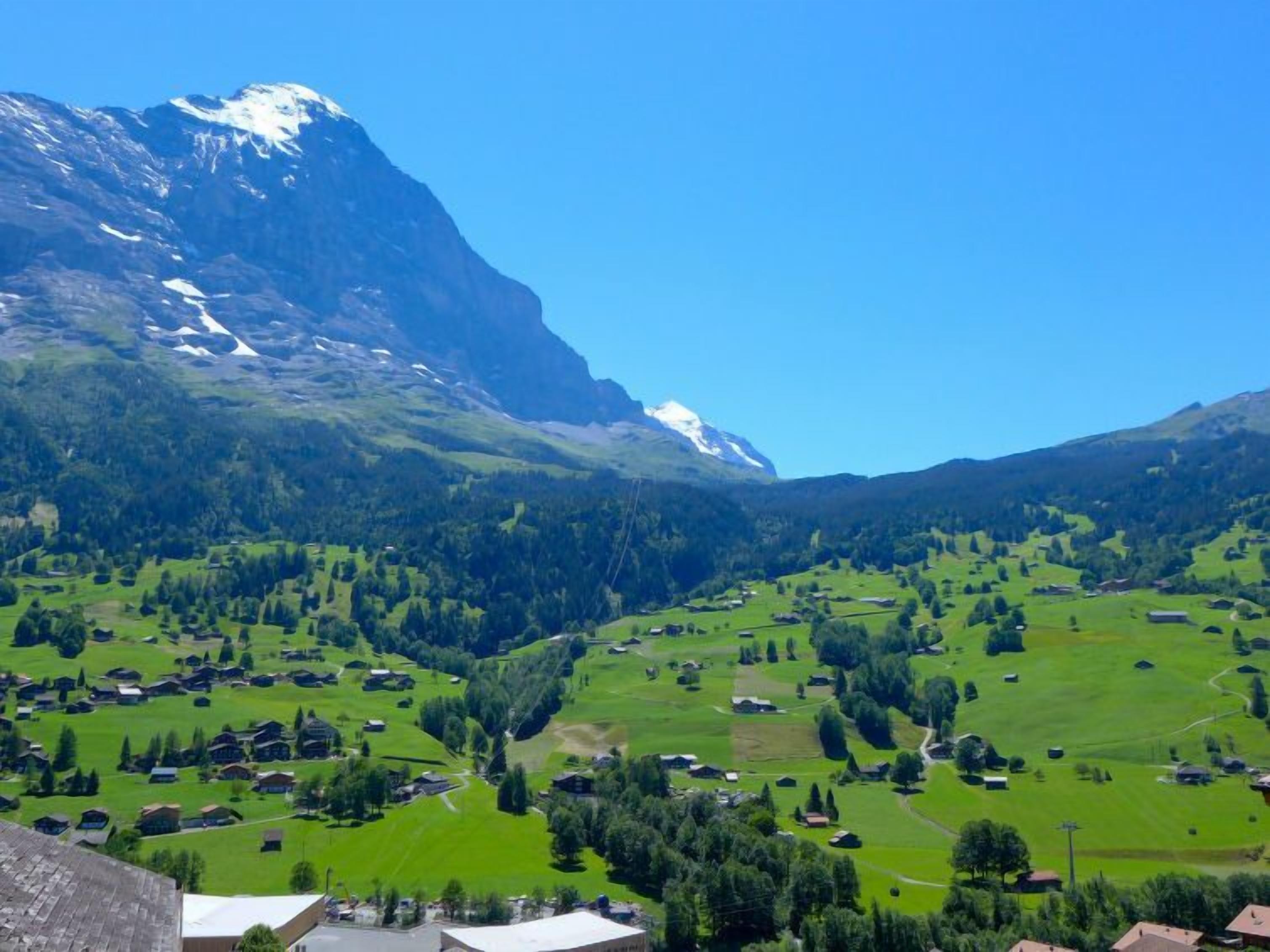 Un paysage montagneux parsemé de maisons, avec un sommet enneigé qui se détache nettement.