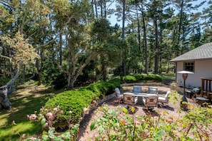 Un patio amueblado con jardín y vistas a un área boscosa.
