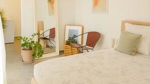 A bedroom with a bed, a desk, chairs, a mirror, and a hanging light fixture. - Peaceful Penthouse with large Sunny Terrace (Marsaxlokk)