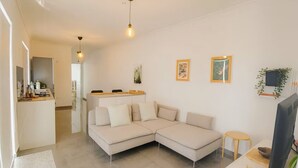 A modern living room with a sectional sofa, a small dining table, and a TV. - Peaceful Penthouse with large Sunny Terrace (Marsaxlokk)