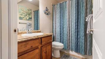 Un baño con tocador de madera, lavamanos blanco y cortina de ducha.