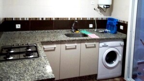 A compact kitchen with a gas stove, a sink, and a washing machine. - Residence Alcazaba Oued Laou 4129 (OUED LAW)