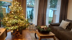 A cozy living room with a decorated Christmas tree, a sofa, and a coffee table with candles. - Naturally happy (170m to the Müritz) (Röbel/Müritz)