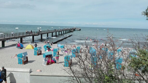 A beach with a pier extending into the sea, featuring beach huts and people relaxing. - Naturally happy (170m to the Müritz) (Röbel/Müritz)