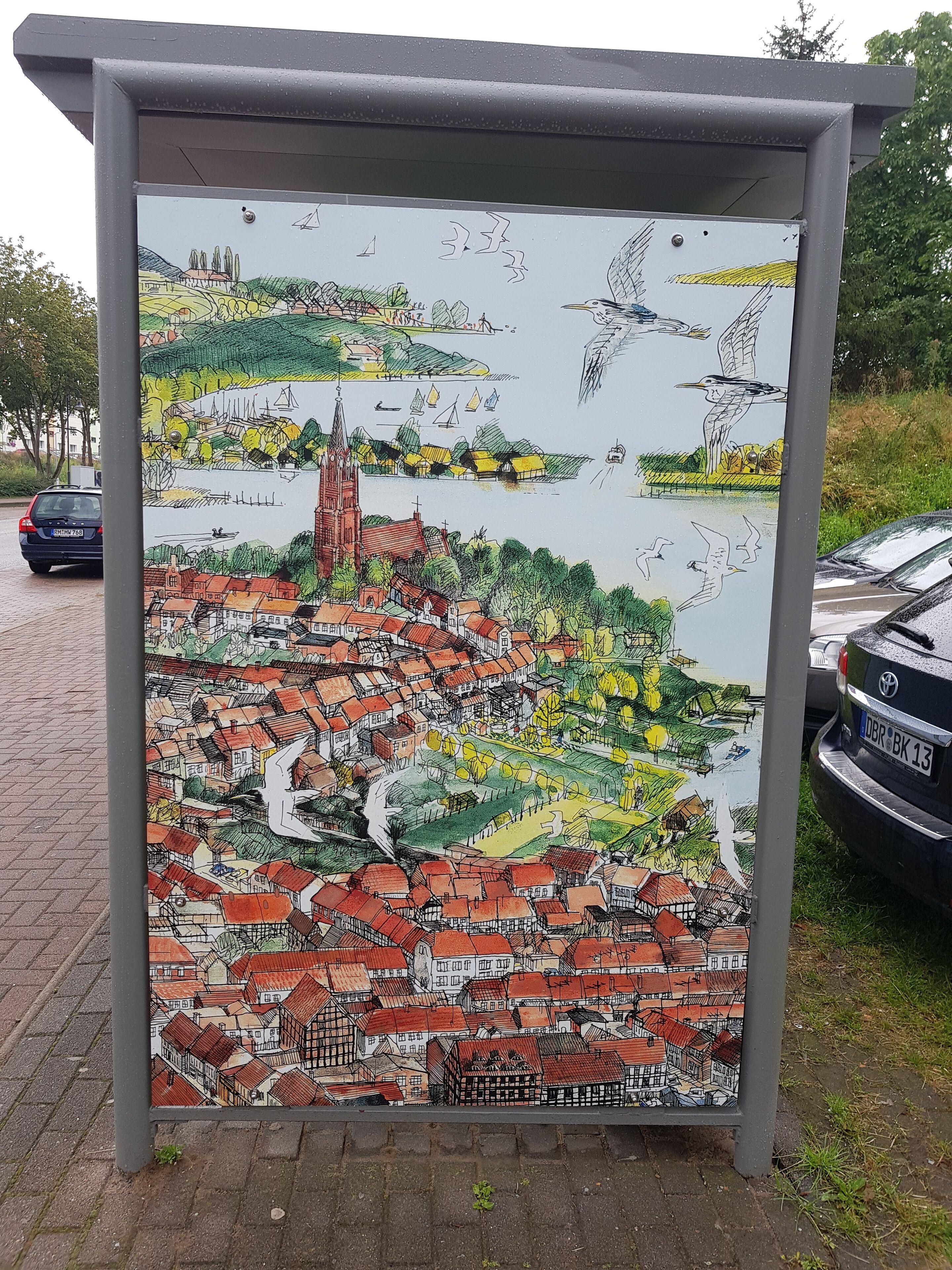 A detailed mural of a town with a prominent church, boats on water, and birds flying.