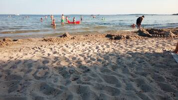 Una playa arenosa con gente nadando y jugando en el agua.