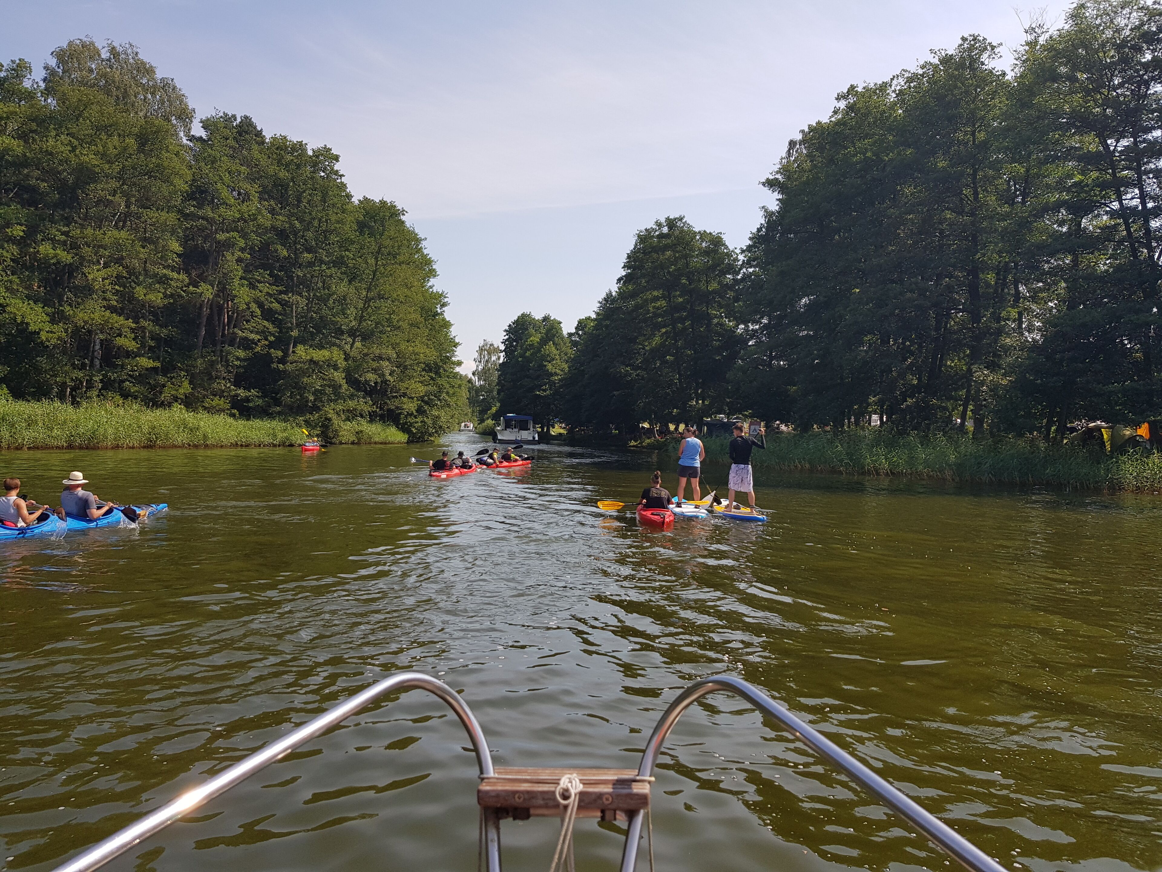 Eine Flusslandschaft mit Menschen, die Kajak fahren und Stand-Up-Paddling betreiben.